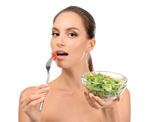 Young woman with fresh vegetable salad on white background - Foto, imagen