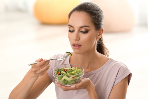 Молодая женщина ест свежий овощной салат дома
 - Фото, изображение