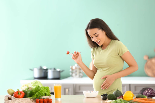 Fiatal terhes nő eszik friss növényi saláta, konyha - Fotó, kép