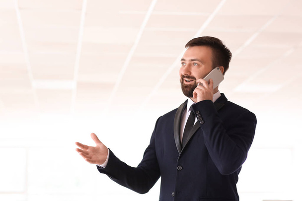 Hezký obchodník mluví přes mobilní telefon v kanceláři - Fotografie, Obrázek