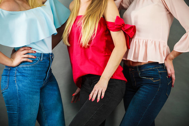 Three unrecognizable women having fashionable outfits, blue jeans and colorful shirts. Fashion and clothing concept. - 写真・画像