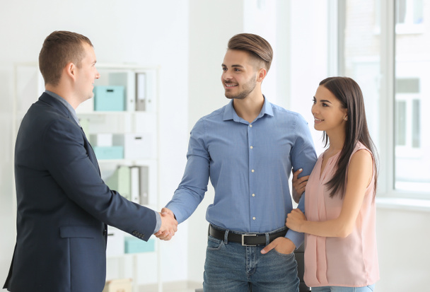 Young man shaking hands with estate agent in office - Фото, изображение