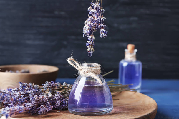 Tropfen ätherisches Lavendelöl in Flasche auf Holzbrett - Foto, Bild