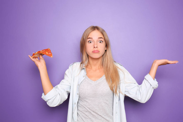 Emotional woman with slice of delicious pizza on color background - Foto, Imagen
