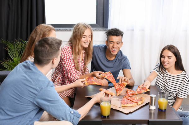 Jovens se divertindo na festa com deliciosa pizza dentro de casa
 - Foto, Imagem