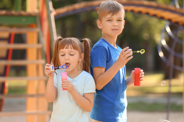 Crianças pequenas bonitos soprando bolhas de sabão ao ar livre
 - Foto, Imagem