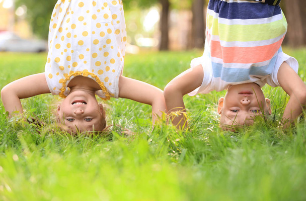 Cute little children standing on head and having fun outdoors - Photo, Image