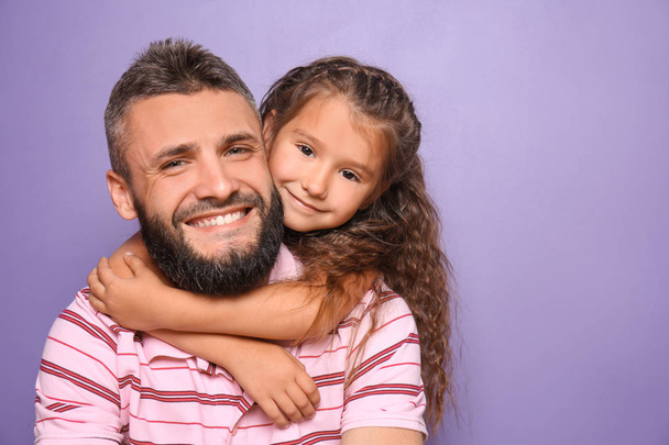 kleines Mädchen umarmt ihren Vater auf farbigem Hintergrund - Foto, Bild