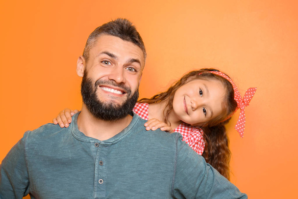 Portrait of father and his little daughter on color background - Photo, image