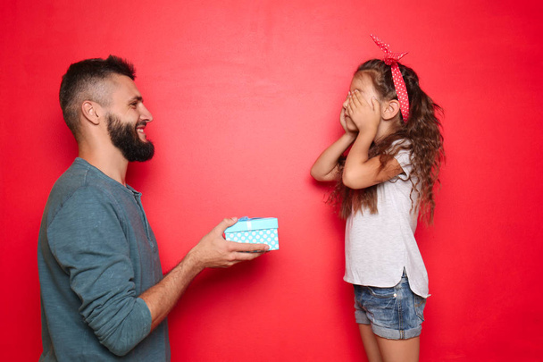 Father giving present to his little daughter on color background - Photo, Image