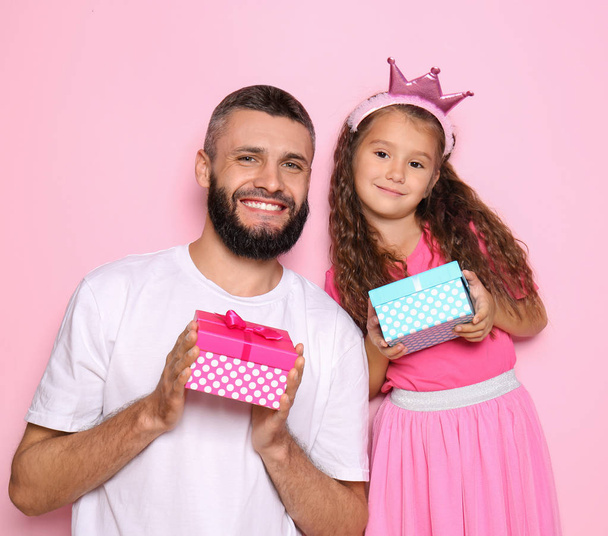 Portrait of father and his little daughter with gift boxes on color background - Fotoğraf, Görsel