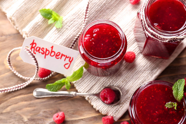 Jars with tasty raspberry jam on wooden table - Photo, Image