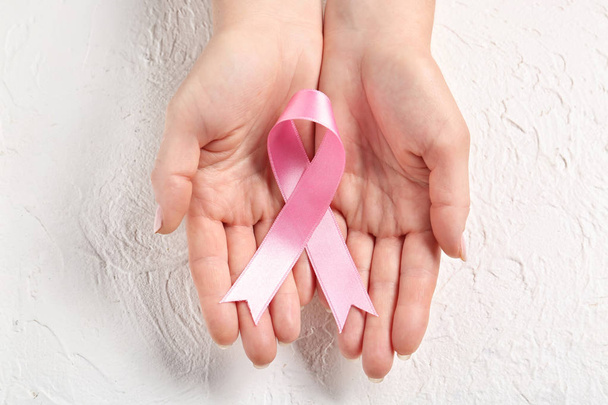 Woman holding pink ribbon on light background. Breast cancer awareness concept - Photo, Image