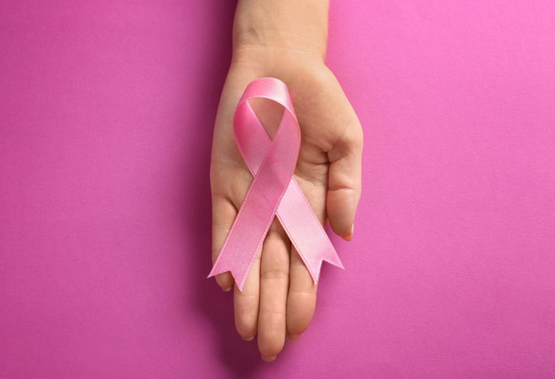 Жінка тримає рожеву стрічку на кольоровому фоні. Концепція обізнаності про рак молочної залози
 - Фото, зображення