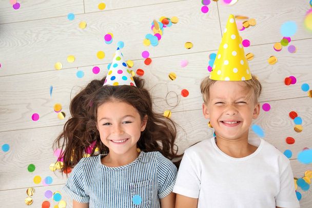 家で誕生日を祝っている間床で横になっているかわいい子供たち - 写真・画像