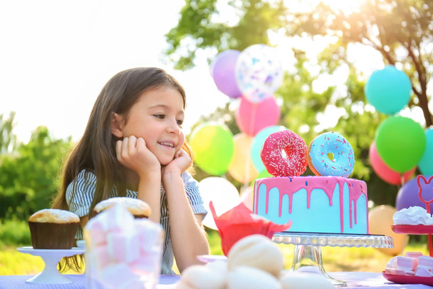 мила дівчинка з тортом святкування Дня народження на відкритому повітрі
 - Фото, зображення