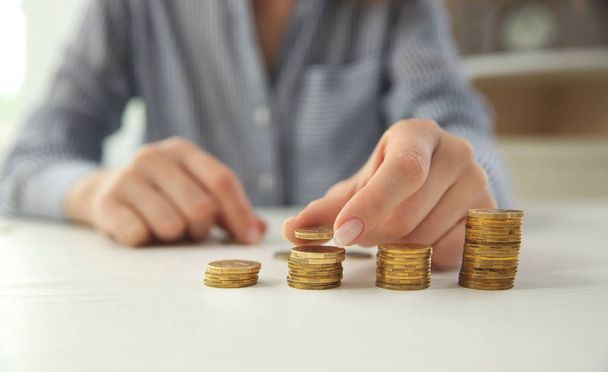 Γυναίκα στοίβαγμα κέρματα στο τραπέζι. Έννοια της αποταμίευσης - Φωτογραφία, εικόνα