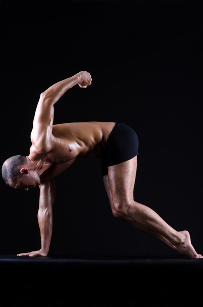 muskulöser Mann im dunklen Studio - Foto, Bild
