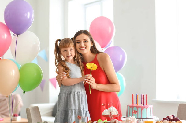 Cute little girl and her mother with beautiful flower at birthday party - Photo, Image