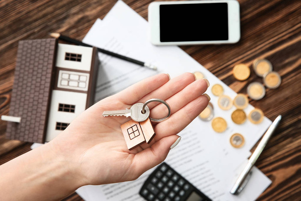 Woman holding key with trinket in shape of house. Mortgage concept - Photo, Image