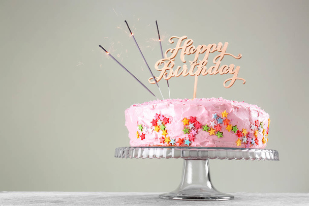 Stand with beautiful tasty birthday cake on table - Фото, зображення