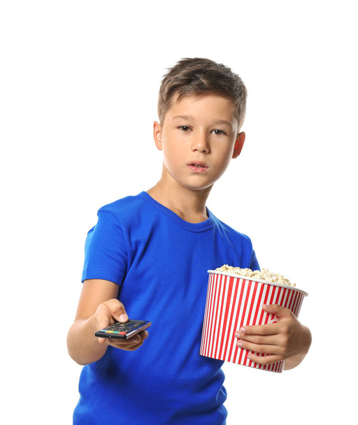 Cute little boy with cup of popcorn switching channels on white background - Фото, зображення