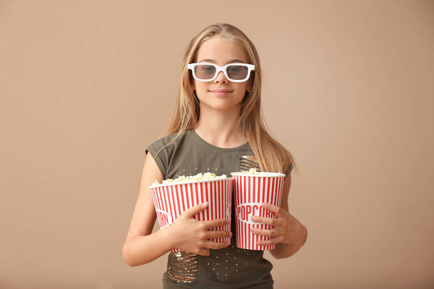 Carino bambina con tazze di popcorn indossando occhiali da cinema 3D su sfondo di colore
 - Foto, immagini