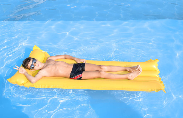Милый маленький мальчик отдыхает на надувном матрасе в бассейне
 - Фото, изображение