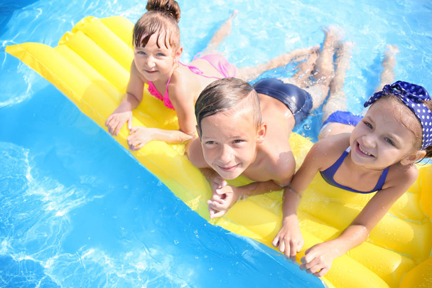 Aranyos gyerekek úszás medencében nyári napon - Fotó, kép