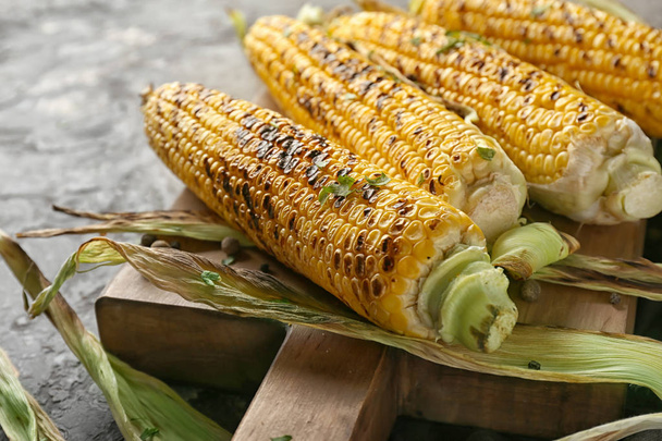 Tasty grilled corn cobs on wooden board, closeup - Photo, Image