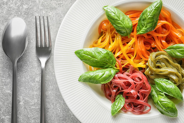 Plate of delicious colorful pasta with basil on table, closeup - Zdjęcie, obraz