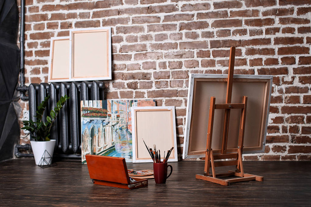 Herramientas de caballete y pintura en el suelo en el taller del artista
 - Foto, Imagen