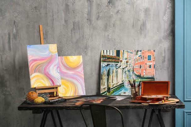 Bellissimi quadri con pennelli e vernici sul tavolo nel laboratorio dell'artista
 - Foto, immagini