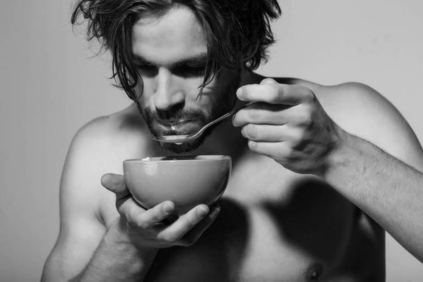 man with bare chest eating breakfast of oatmeal with milk - Valokuva, kuva
