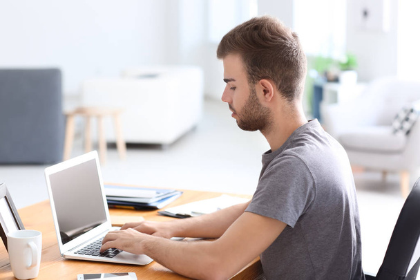 Красавчик, работающий с ноутбуком в офисе
 - Фото, изображение
