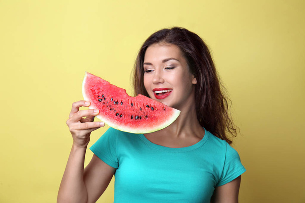 Beautiful young woman with slice of tasty watermelon on color background - Фото, изображение