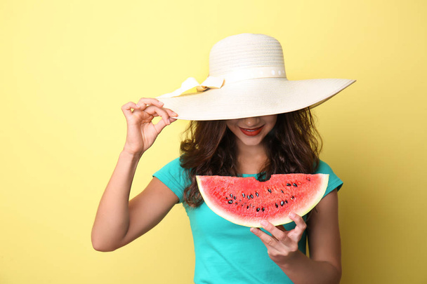 Красивая молодая женщина с ломтиком вкусного арбуза на цветном фоне
 - Фото, изображение