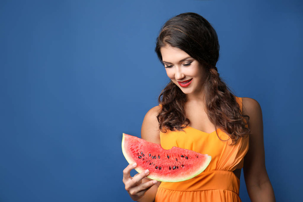 Όμορφη νεαρή γυναίκα με φέτα καρπούζι νόστιμο σε χρώμα φόντου - Φωτογραφία, εικόνα