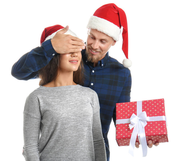 Young man giving his girlfriend Christmas present on white background - Photo, Image