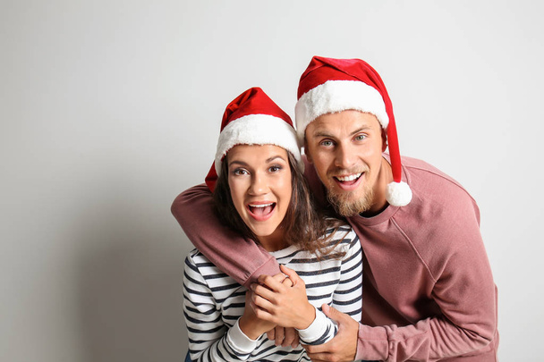 Drôle de portrait de mignon jeune couple dans chapeaux de Père Noël sur fond clair
 - Photo, image