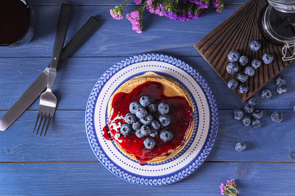Plate with tasty pancakes, jam and blueberries on wooden table - Photo, image