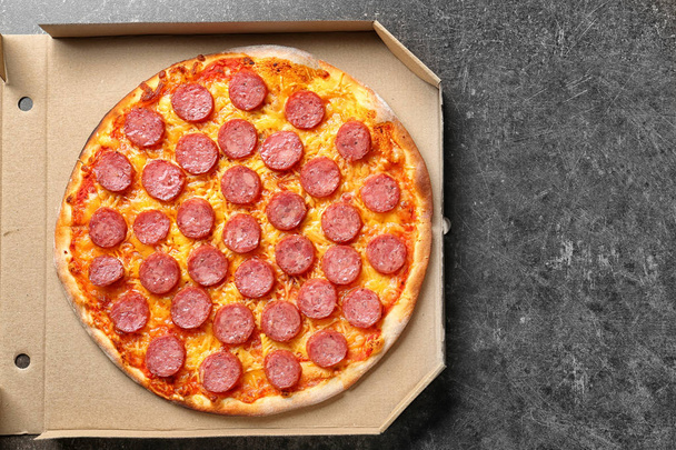 Смачна піца Пепероні в картонній коробці на темному столі
 - Фото, зображення