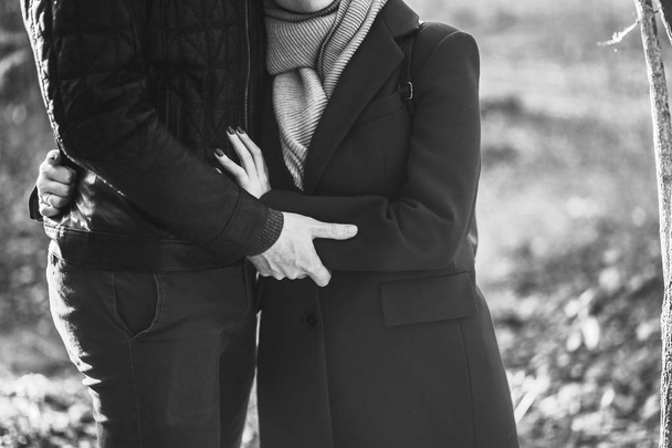 Przycięty obraz Młoda para w miłość, kobieta mężczyzna w ubranie, obejmując trzymając ręce na spacer w jesienny park miejski na zewnątrz. Kocham pojęcia styl życia rodziny osób relacji. Czarno-białe zdjęcie - Zdjęcie, obraz