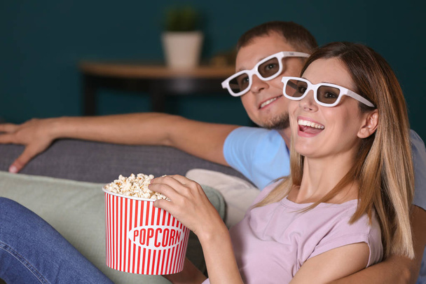 Couple eating popcorn while watching TV in evening - Foto, imagen