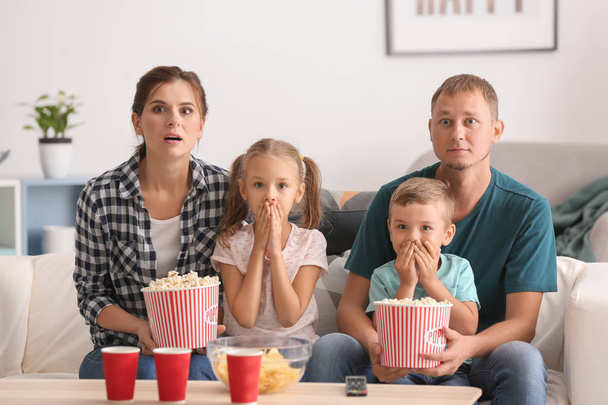 Family eating popcorn while watching scary movie at home - Foto, Imagem