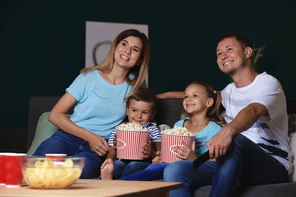 Happy family watching TV and eating popcorn in evening - Fotó, kép