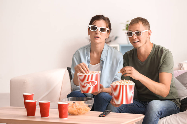 Pari syö popcornia katsoessaan televisiota kotona
 - Valokuva, kuva