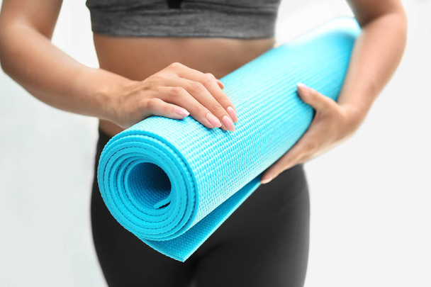 Young woman with yoga mat on white background, closeup - Φωτογραφία, εικόνα
