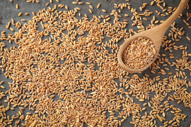 Ложка і зерна пшениці на сірому фоні
 - Фото, зображення