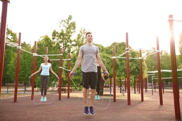 Group of sporty people jumping rope on athletic field outdoors - Photo, Image